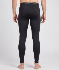 Manlig modell visar ett par svarta Clima Pants lager-2 underställsbyxor. Modellen visar byxorna bakifrån i en studio med ljusgrå bakgrund.