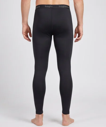 Manlig modell visar ett par svarta Clima Pants lager-2 underställsbyxor. Modellen visar byxorna bakifrån i en studio med ljusgrå bakgrund.