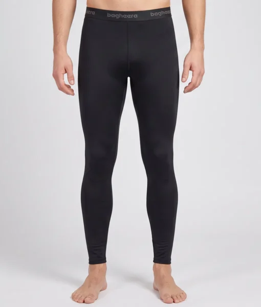 Manlig modell visar ett par svarta Clima Pants lager-2 underställsbyxor. Modellen visar byxorna framifrån i en studio med ljusgrå bakgrund.