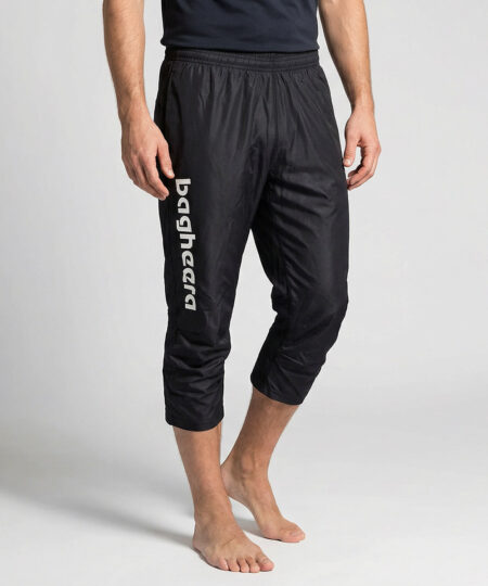 Manlig modell visar ett par svarta knälånga tunna orienteringsbyxor. Modellen strår snett framifrån i en studio med ljusgrå bakgrund.