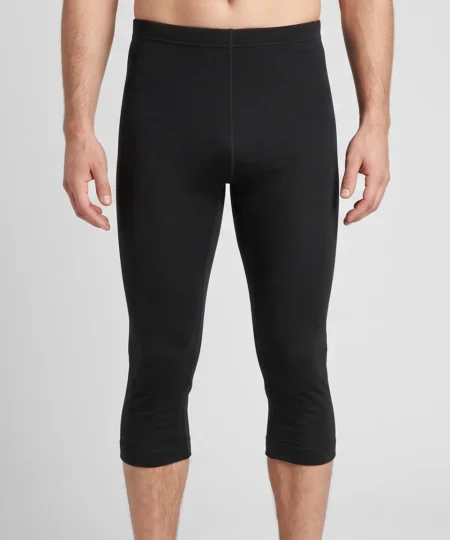 Manlig modell visar ett par svarta knälånga lite tjockare underställsbykor. Modellen visar byxorna framifrån i en studio med ljusgrå bakgrund.