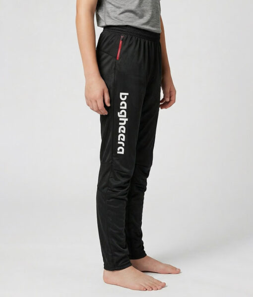 Killmodell i 12 års åldern visar ett par svarta långa tunna orienteringsbyxor. Modellen strår snett framifrån i en studio med ljusgrå bakgrund.