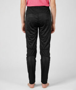 Tjejmodell i 12 års åldern visar ett par svarta långa tunna orienteringsbyxor. Modellen strår bakifrån i en studio med ljusgrå bakgrund.