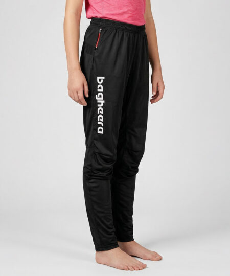 Tjejmodell i 12 års åldern visar ett par svarta långa tunna orienteringsbyxor. Modellen strår snett framifrån i en studio med ljusgrå bakgrund.