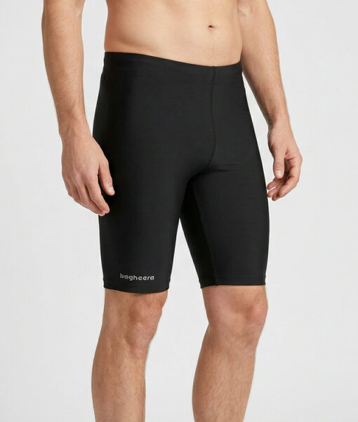 Manlig modell visar ett par svarta korta funktionstights. Modellen står snett framifrån i en studio med ljusgrå bakgrund.