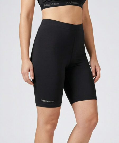 Kvinnlig modell visar ett par svarta korta tränings tights. Modellen står framifrån i en studio med ljusgrå bakgrund.