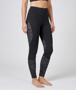 Kvinnlig modell visar ett par svarta mörkgrå träningstights med hög midja och mönstrad mesh. Modellen strår framifrån i en studio med ljusgrå bakgrund.