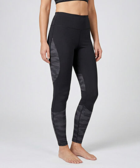 Kvinnlig modell visar ett par svarta mörkgrå träningstights med hög midja och mönstrad mesh. Modellen strår framifrån i en studio med ljusgrå bakgrund.