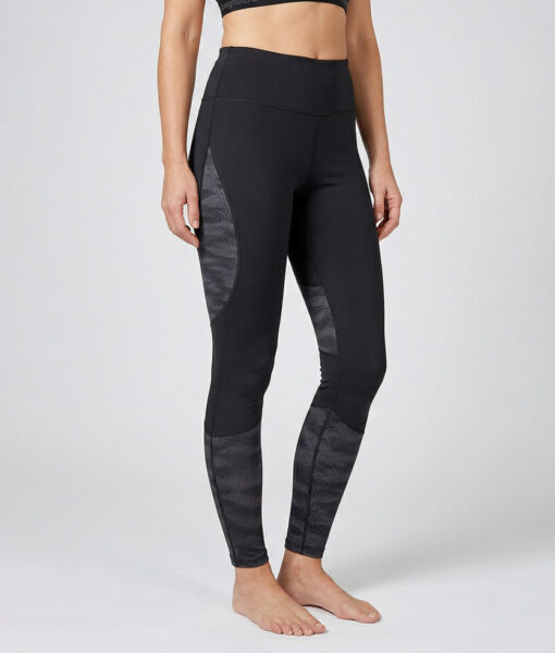Kvinnlig modell visar ett par svarta mörkgrå träningstights med hög midja och mönstrad mesh. Modellen strår framifrån i en studio med ljusgrå bakgrund.