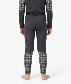 Mörkgrå underställsbyxa i 100% merino med grått dalecarlianmönster nere vid vaderna för barn. Bilden visar en modell bakifrån.