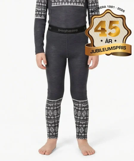Pojkmodell visar ett par gråa underställsbyxor i 100% merino med ljusgrått dalecarlianmönster på underbenen. Modellen visar byxorna framifrån i en studio med grå bakgrund.