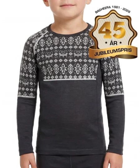 Pojkmodell visar en mörkgrå underställströja i 100% merino med grått dalecarlianmönster upptill och på överarmarna för barn. Modellen visar tröjan framifrån i en studio med grå bakgrund.