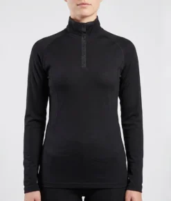 Kvinlig modell visar en svart långärmad polo underställströja i 100% merinoull. Modellen visar tröjan framifrån mot en ljusgrå bakgrund.