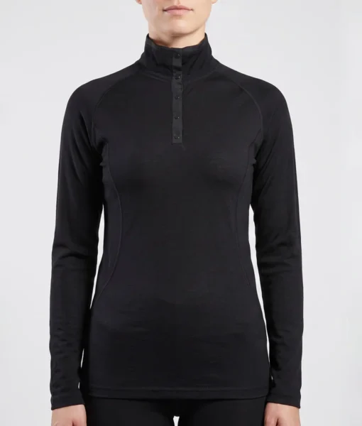 Kvinlig modell visar en svart långärmad polo underställströja i 100% merinoull. Modellen visar tröjan framifrån mot en ljusgrå bakgrund.