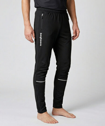 Manlig modell visar ett par svarta långa funktionsträningsbyxor. Modellen står snett framifrån i en studio med ljusgrå bakgrund.