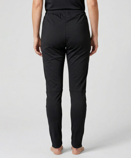 Kvinnlig modell visar ett par svarta långa funktions träningsbyxor. Modellen står bakifrån i en studio med ljusgrå bakgrund.