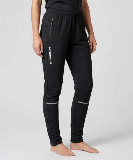 Kvinnlig modell visar ett par svarta långa funktions träningsbyxor. Modellen står framifrån i en studio med ljusgrå bakgrund.