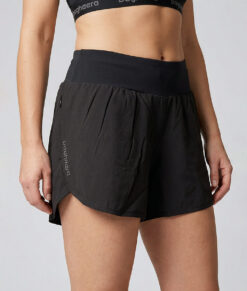 Kvinnlig modell visar ett par svarta korta tränings shorts. Modellen står snett framifrån i en studio med ljusgrå bakgrund.