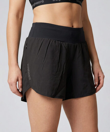 Kvinnlig modell visar ett par svarta korta tränings shorts. Modellen står snett framifrån i en studio med ljusgrå bakgrund.