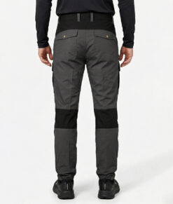 Manlig modell visar ett par gråa långa friluftsbyxor. Modellen står snett bakifrån i en studio med ljusgrå bakgrund.