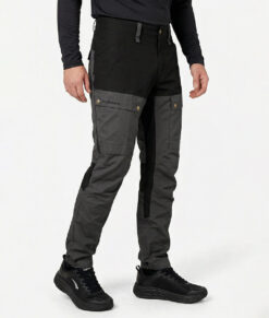 Manlig modell visar ett par gråa långa friluftsbyxor. Modellen står snett framifrån i en studio med ljusgrå bakgrund.