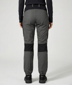 Kvinlig modell visar ett par gråa långa friluftsbyxor. Modellen står snett bakifrån i en studio med ljusgrå bakgrund.