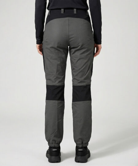 Kvinlig modell visar ett par gråa långa friluftsbyxor. Modellen står snett bakifrån i en studio med ljusgrå bakgrund.