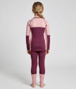 Merino Brisk är ett rosa/vinrött underställ för barn som är tillverkat i den perfekta kombinationen av material. Vi har blandat merinoull tillsammans med lyocell, som är en miljövänlig regenatfiber tillverkad av cellulosa. Bilden visar en modelltjej bakifrån.