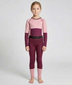 Merino Brisk är ett rosa/vinrött underställ för barn som är tillverkat i den perfekta kombinationen av material. Vi har blandat merinoull tillsammans med lyocell, som är en miljövänlig regenatfiber tillverkad av cellulosa. Bilden visar en modelltjej framifrån.