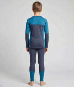 Merino Brisk är ett turkost/marinblått underställ för barn som är tillverkat i den perfekta kombinationen av material. Vi har blandat merinoull tillsammans med lyocell, som är en miljövänlig regenatfiber tillverkad av cellulosa. Bilden visar en modellkille bakifrån.