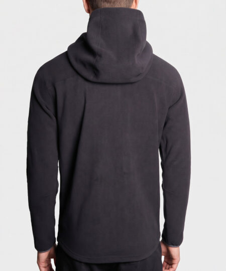 Manlig modell visar en svart långärmad lager-2 fleecejacka med huva. Modellen visar jackan bakifrån i en studio med ljusgrå bakgrund.