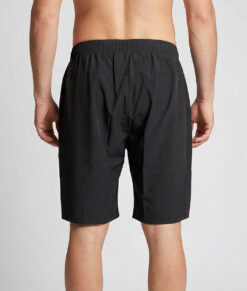 Manlig modell visar ett par svarta längre shorts. Modellen står bakifrån i en studio med ljusgrå bakgrund.