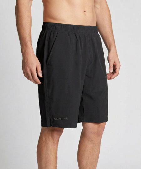 Manlig modell visar ett par svarta längre shorts. Modellen står snett framifrån i en studio med ljusgrå bakgrund.