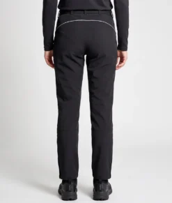Kvinlig modell visar ett par svarta vinter softshell byxor. Modellen står bakifrån i en studio med ljusgrå bakgrund.