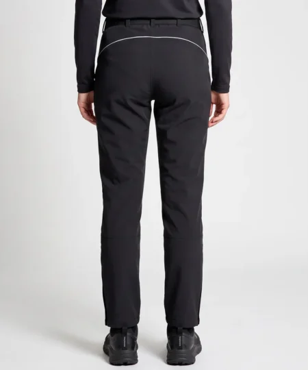 Kvinlig modell visar ett par svarta vinter softshell byxor. Modellen står bakifrån i en studio med ljusgrå bakgrund.
