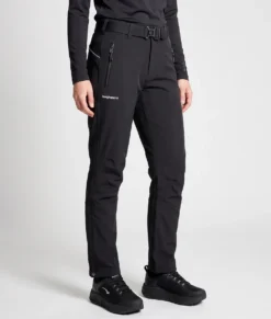 Kvinlig modell visar ett par svarta vinter softshell byxor. Modellen står snett framifrån i en studio med ljusgrå bakgrund.