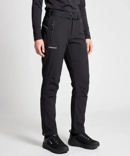 Kvinlig modell visar ett par svarta vinter softshell byxor. Modellen står snett framifrån i en studio med ljusgrå bakgrund.