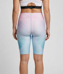 Kvinnlig modell visar ett par mintgröna och rosa korta tränings tights. Modellen står bakifrån i en studio med ljusgrå bakgrund.