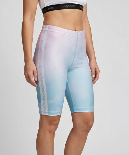 Kvinnlig modell visar ett par mintgröna och rosa korta tränings tights. Modellen står snett framifrån i en studio med ljusgrå bakgrund.