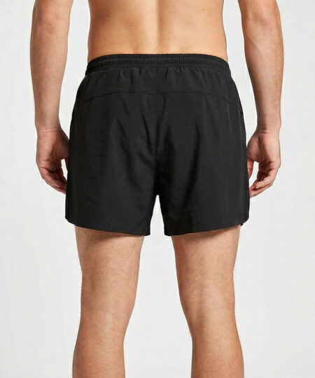 Manlig modell visar ett par svarta sprint shorts. Modellen står bakifrån i en studio med ljusgrå bakgrund.