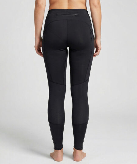 Kvinnlig modell visar ett par svarta löpartights . Modellen strår bakifrån i en studio med ljusgrå bakgrund.