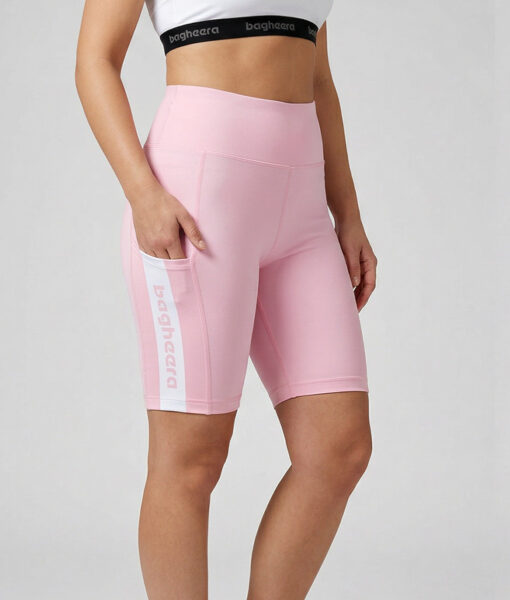 Kvinlig modell visar ett par rosa korta tights. Modellen har ena handen i fickan för att visa att tightsen har fickor. Modellen står snett framifrån i en studio med ljusgrå bakgrund.