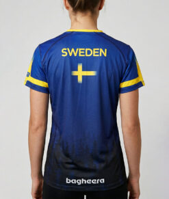 Kvinlig modell visar en blå luftig orienterings t-shirt för dam. Svenska flaggan. Modellen står bakifrån i en studio med ljusgrå bakgrund.