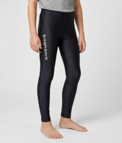 En killmodell i 12 års åldern visar ett par svarta enklare långa tights. Modellen står framifrån i en studio med ljusgrå bakgrund.