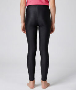 En tjejmodell i 12 års åldern visar ett par svarta enklare långa tights. Modellen står bakifrån i en studio med ljusgrå bakgrund.