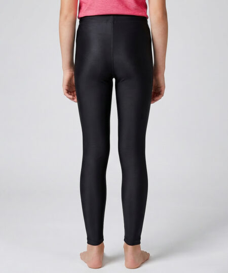 En tjejmodell i 12 års åldern visar ett par svarta enklare långa tights. Modellen står bakifrån i en studio med ljusgrå bakgrund.