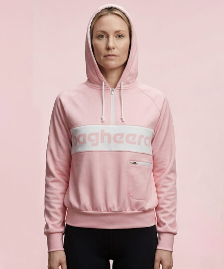 Kvinlig modell visar en rosa klassisk bagheera montana wct hoodie för dam. Modellen står framifrån med huvan på i en studio med ljusrosa bakgrund.
