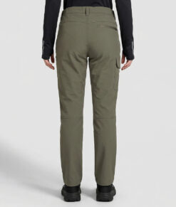 Kvinnlig modell visar ett par skogsgröna långa friluftsbyxor. Modellen strår bakifrån i en studio med ljusgrå bakgrund.