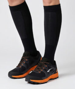 Modell visar svarta orangefärgade bagheera feral r1 orienterings-skor. Modellen står framifrån i en studio med ljusgrå bakgrund.