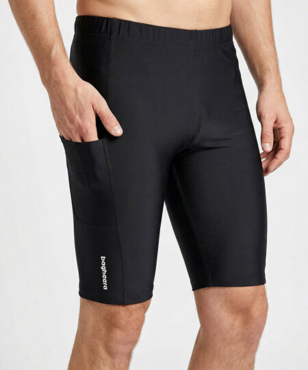 Manlig modell visar ett par svarta korta tights. Modellen har ena handen i fickan för att visa att tightsen har fickor. Modellen står framifrån i en studio med ljusgrå bakgrund.